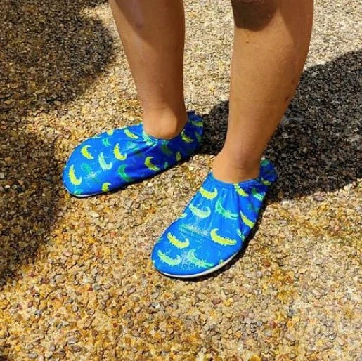 A boy wearing a pair of swim shoes by Slipfree, style Alligator ,in blue and green.