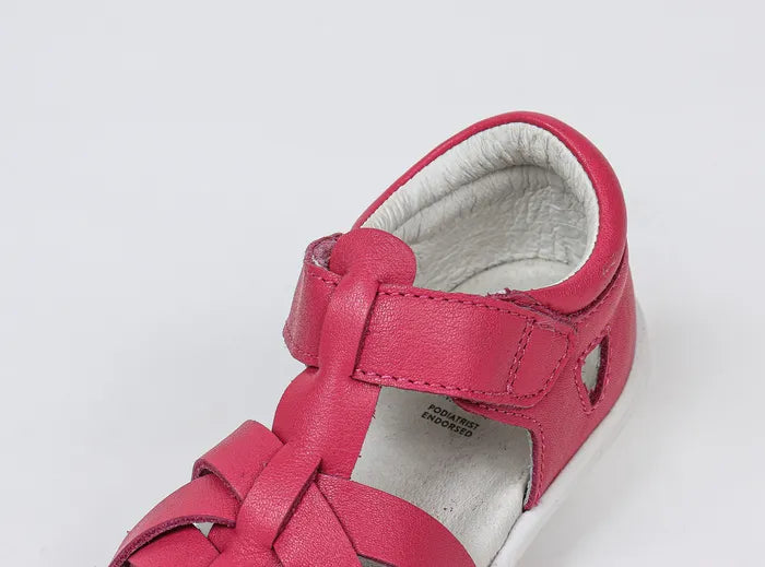 A girls open toe sandal by Bobux, style Tropicana in bright pink with velcro fastening. side view.