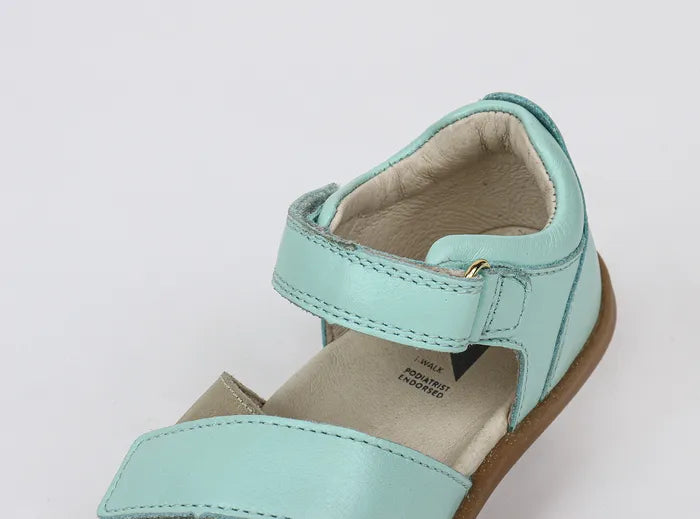 A girls open toe sandal by Bobux, style Sail, in mint and gold with velcro fastening. Close up view.