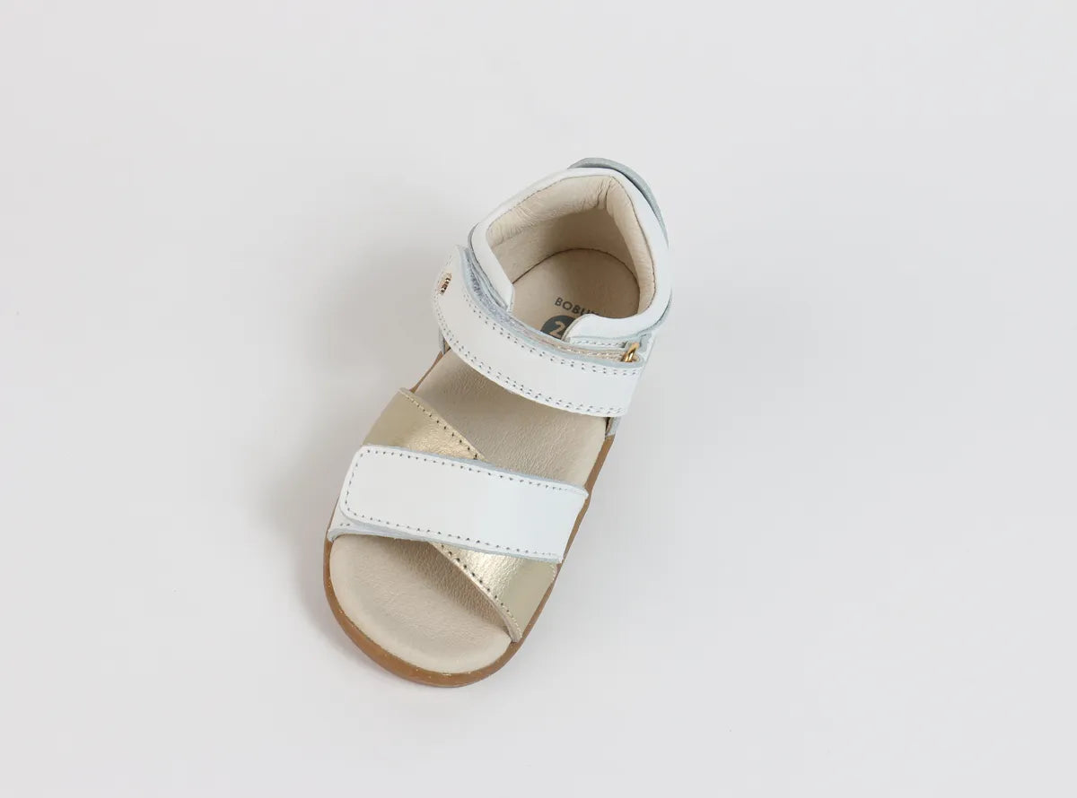 A girls open toe sandal by Bobux, style Sail, in white and gold with velcro fastening. Above view.