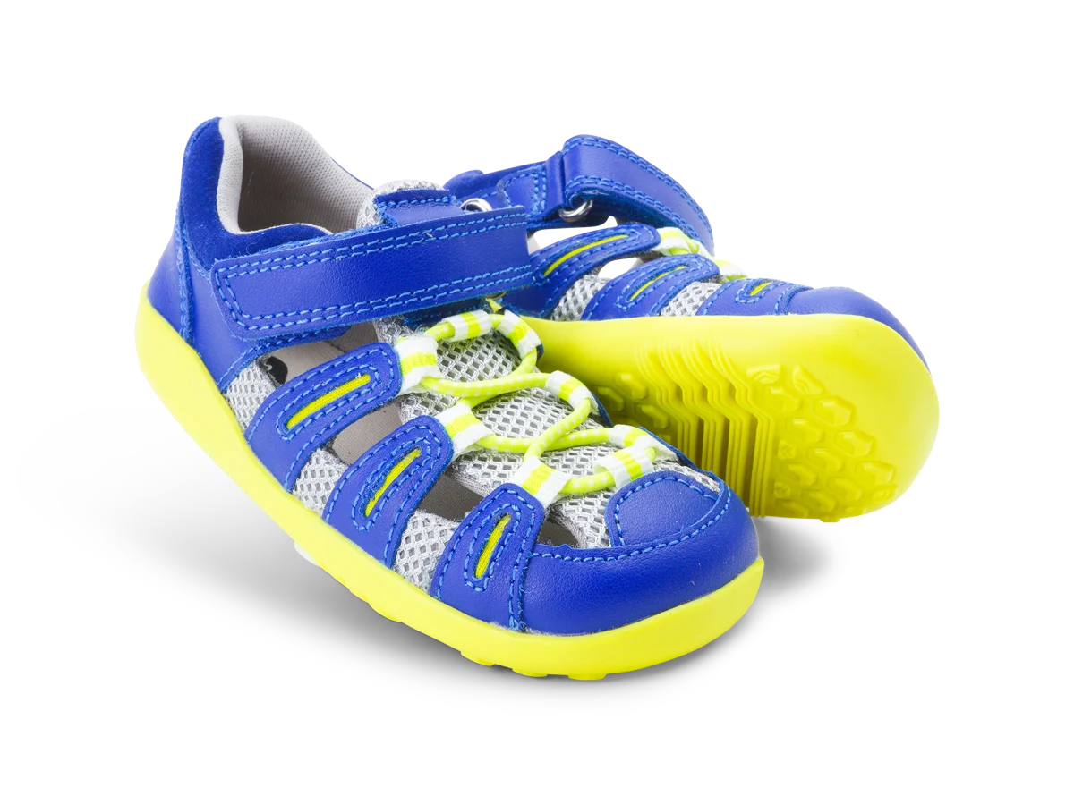 A pair of unisex sandals by Bobux, style Summit,in blue leather/microfibre with neon yellow sole and trim and velcro/elastic fastening. Angled view.