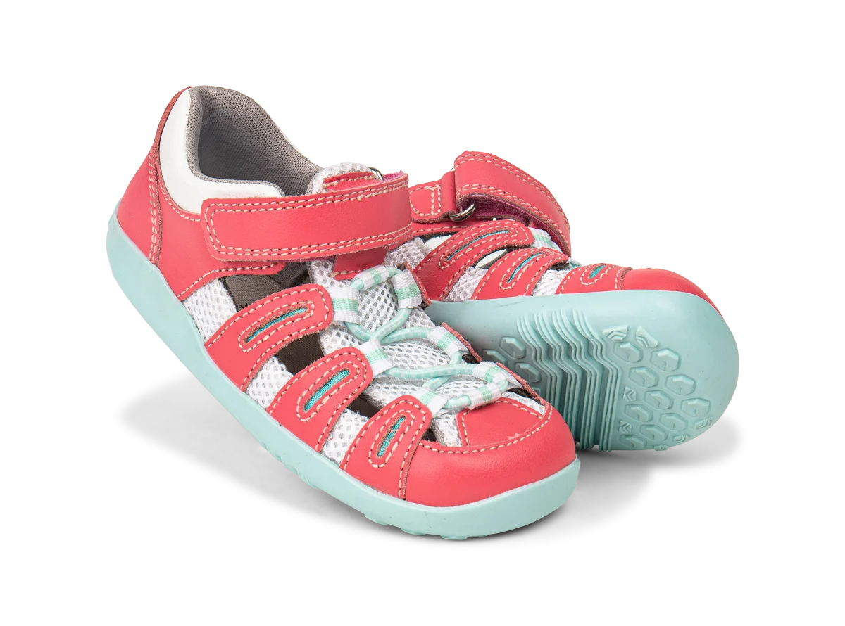 A pair of girls closed toe sandals by Bobux, style Summit,in pink leather/microfibre with pale blue sole and trim and velcro/elastic fastening. Angled view.