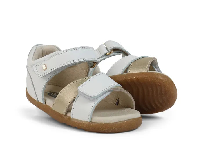 A pair of girls open toe sandals by Bobux, style Sail, in white and gold with velcro fastening. Right side view.