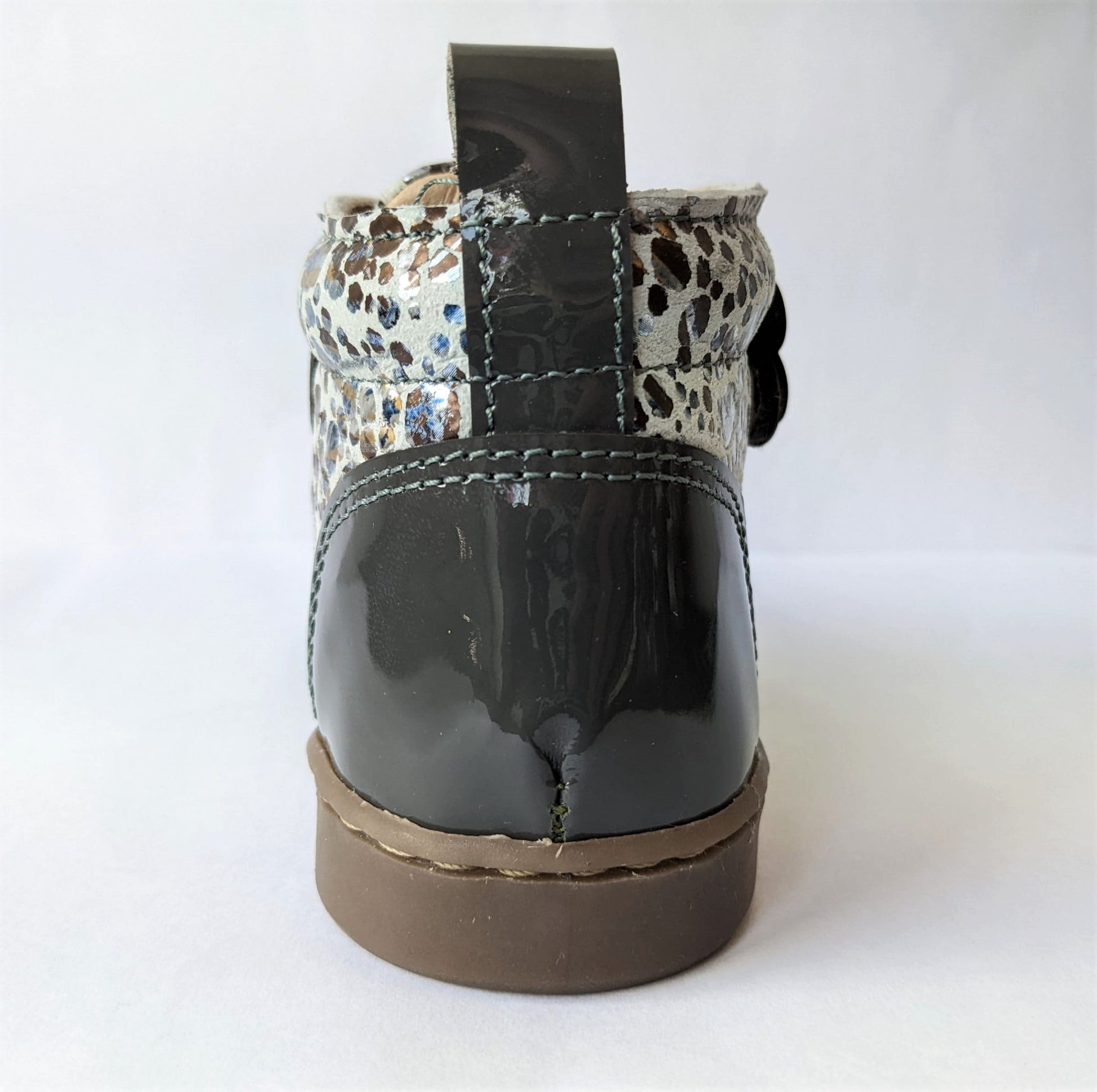 A girls ankle boot by Petasil, style Drean 3, in grey patent with double velcro fastening. Back view.