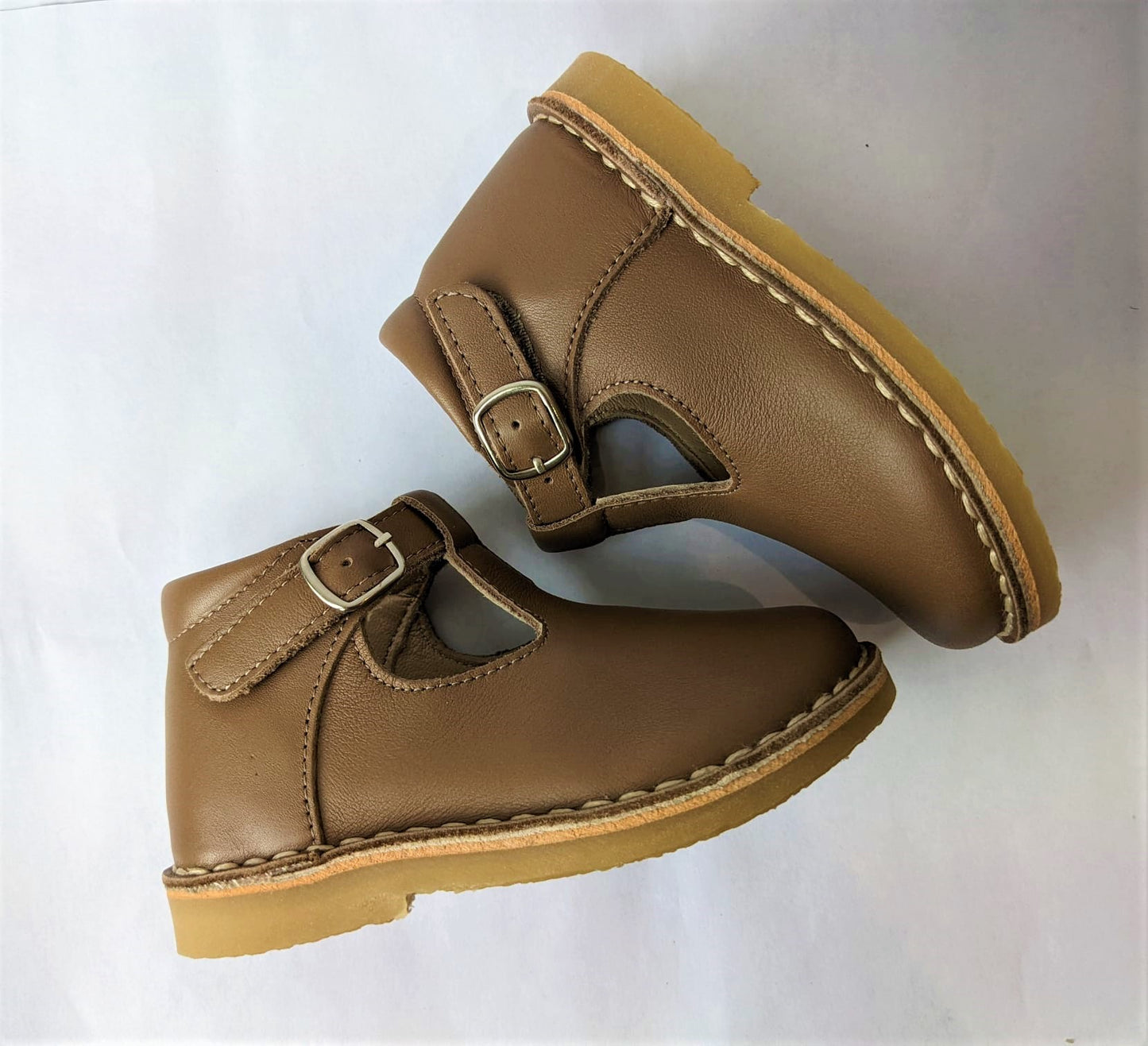A girls T-Bar shoe by Petasil, style Cooper, in light brown with faux buckle fastening. Top view of a pair.
