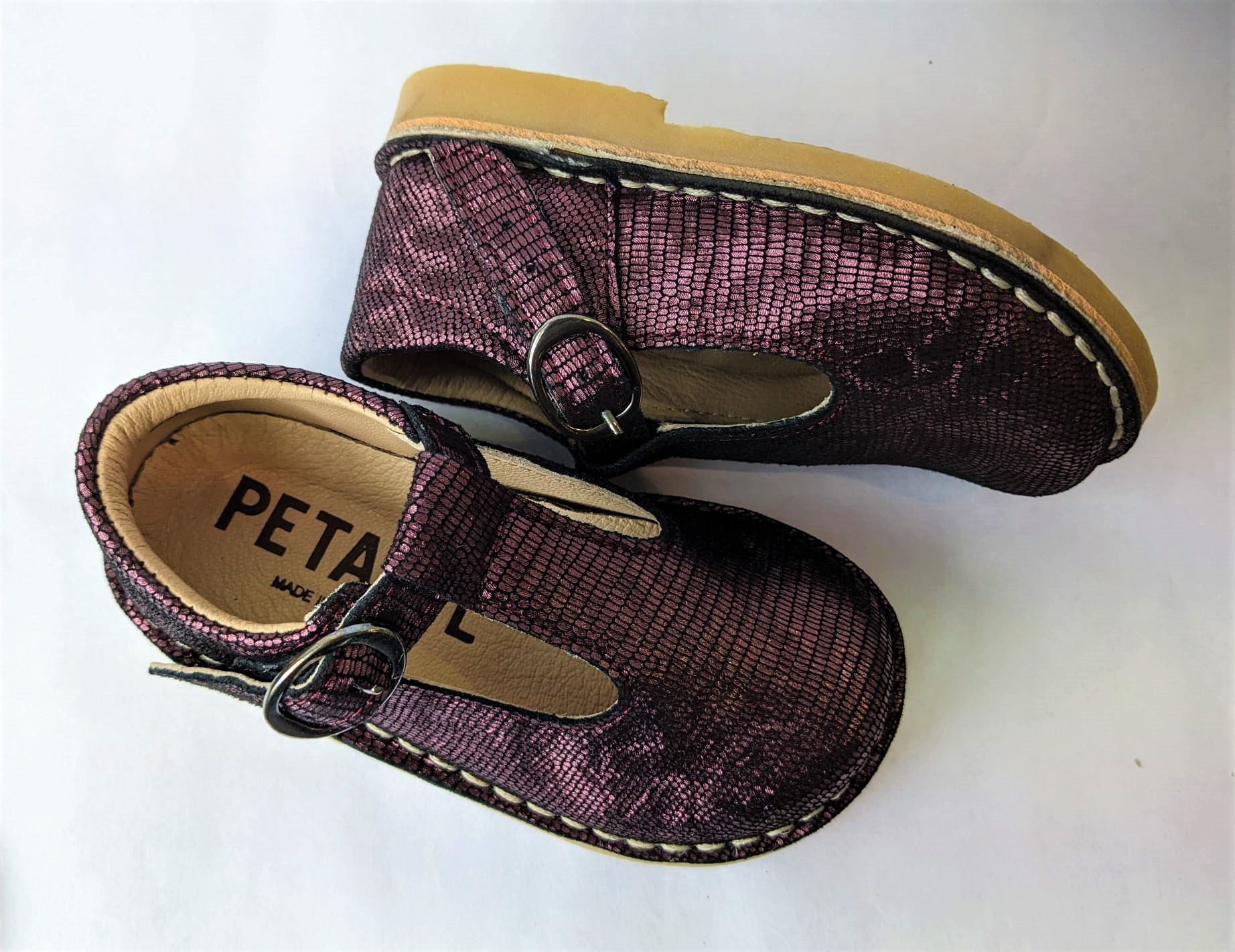 A girls T-Bar shoe by Petasil, style Crosspatch, in bordo with buckle fastening. Top view of a pair.