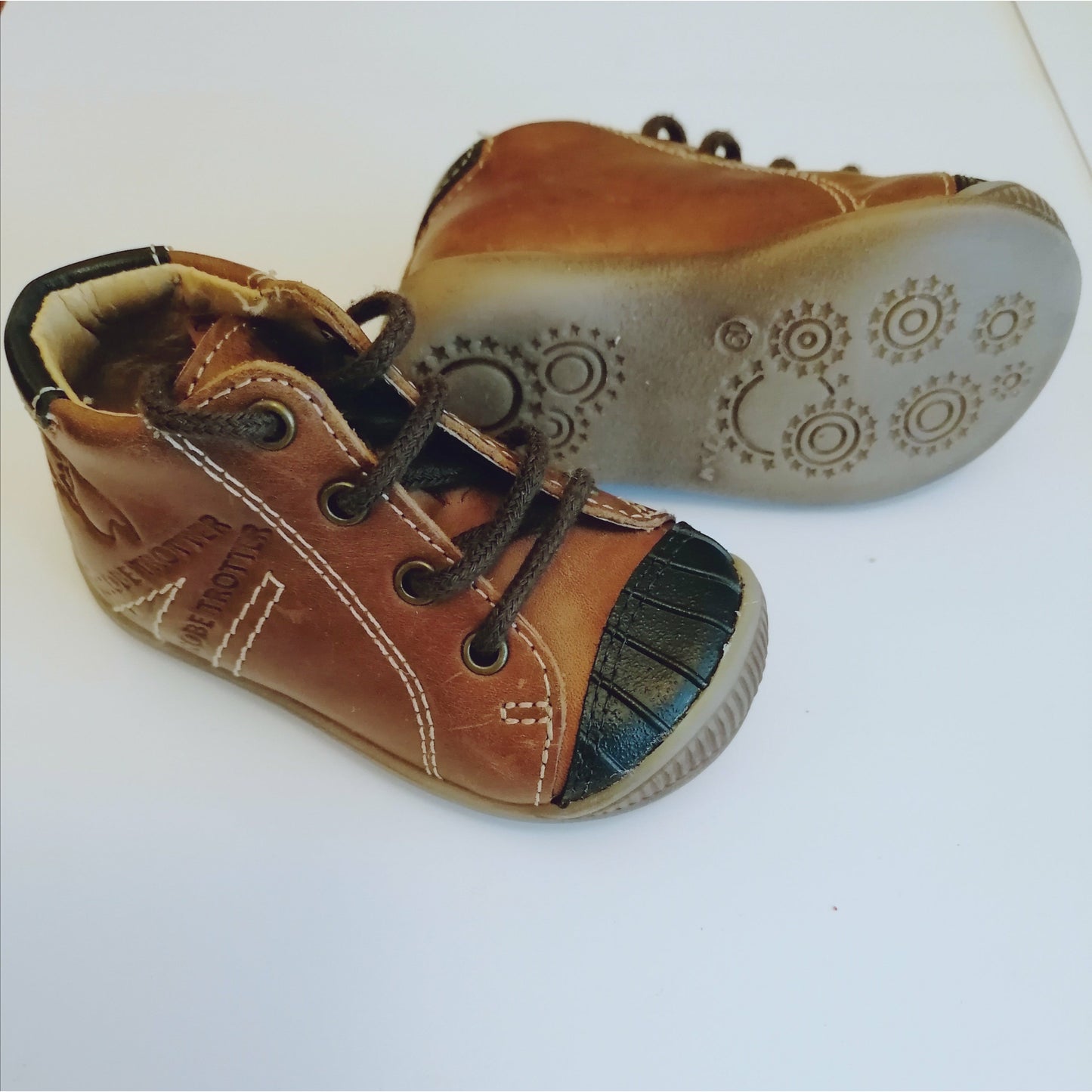 A boys ankle boot by GBB, style Noe, Brown leather lace-up with black rubber toe bumper. Right side view, left view of light brown sole.
