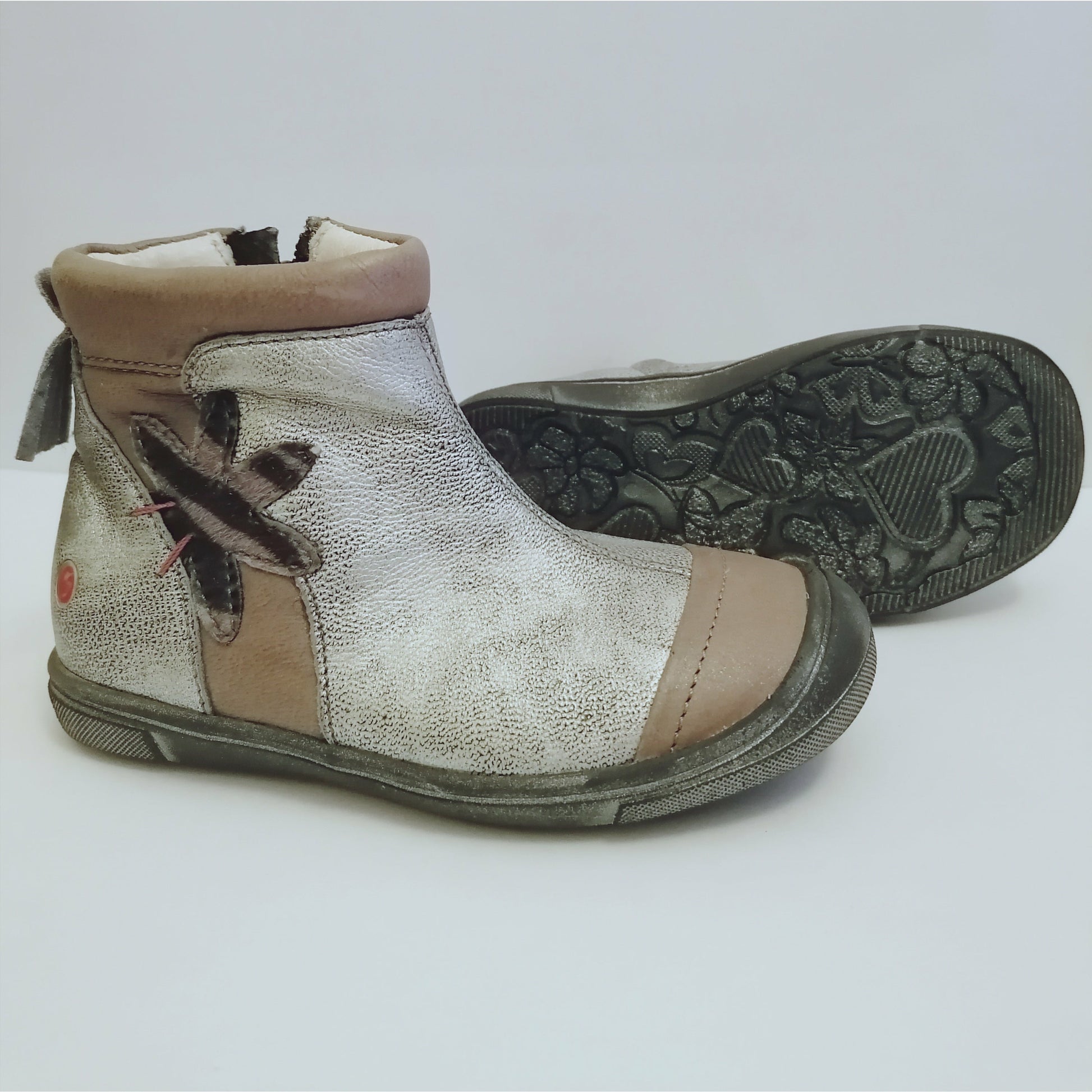 A girls boot by GBB, silver metallic with taupe leather panels and side detail, zip up with rubber toe. Right side view, left view of distressed sole.