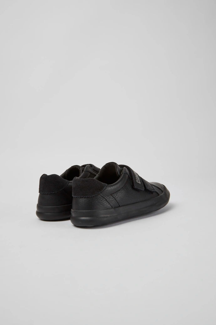 A pair of boys casual school shoes by Camper, style K800415-001,in black leather with double velcro fastening. Angled view.