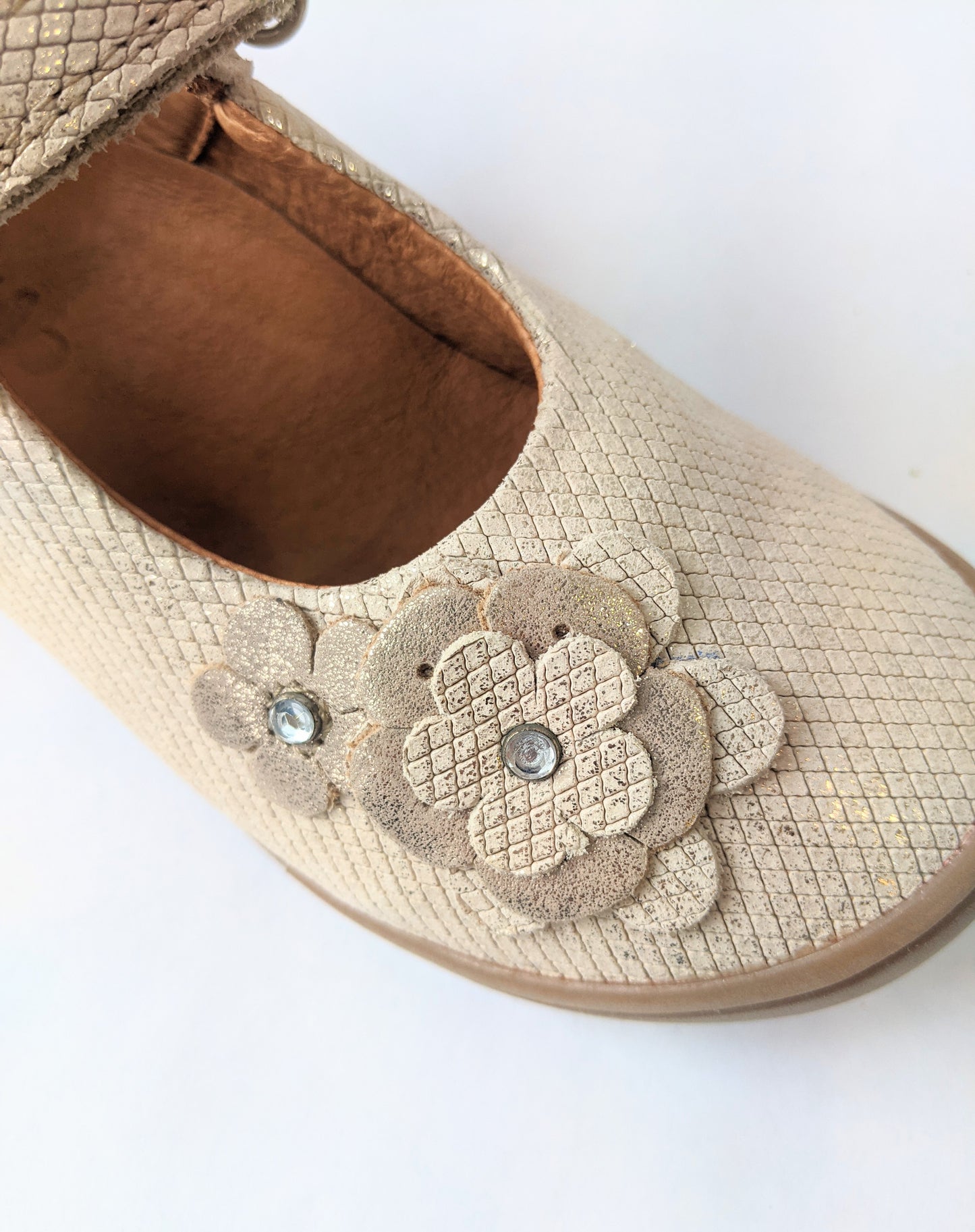 A girls Mary-Jane shoe by Froddo, style G3140089-3A in gold leather with velcro fastening. Close up view of flower embellishment.