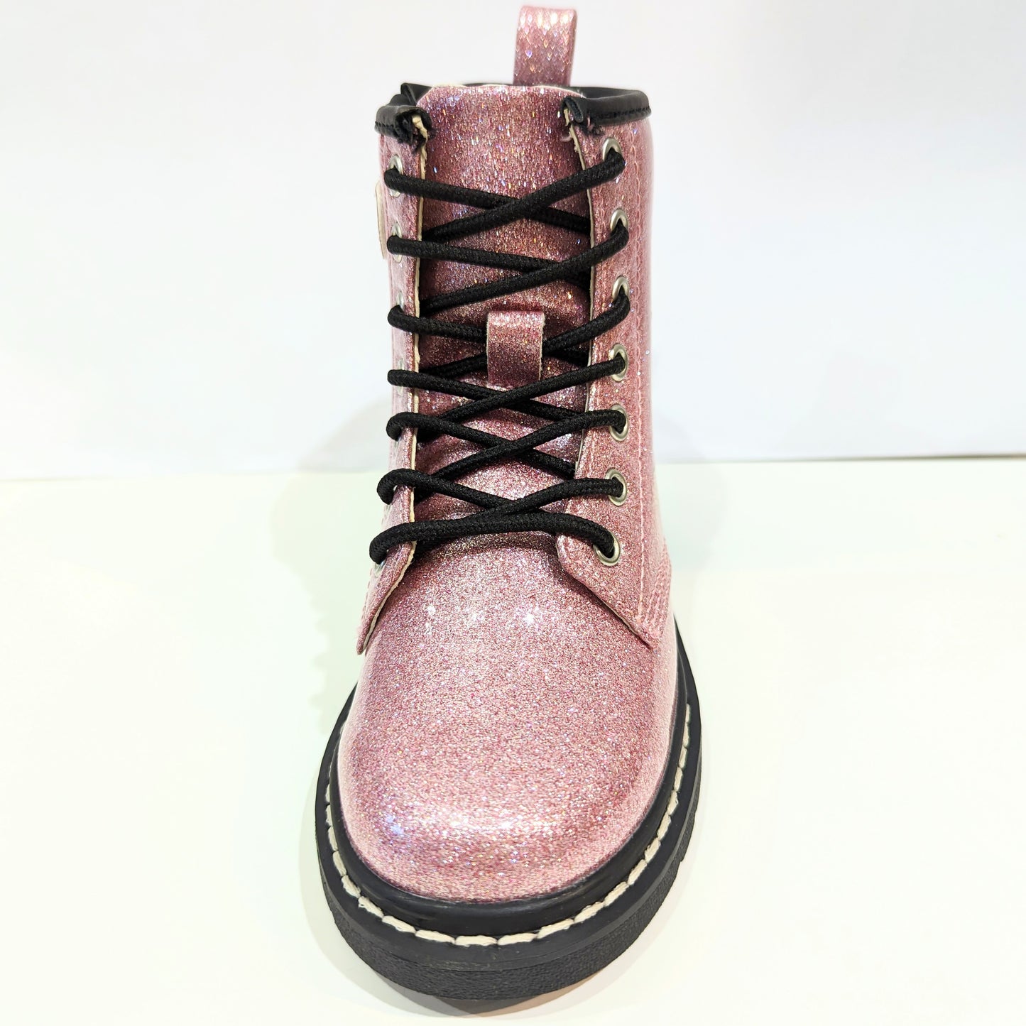 A girls boot by Lelli Kelly, style Emma, in pink glitter patent with zip and lace fastening. Front view.