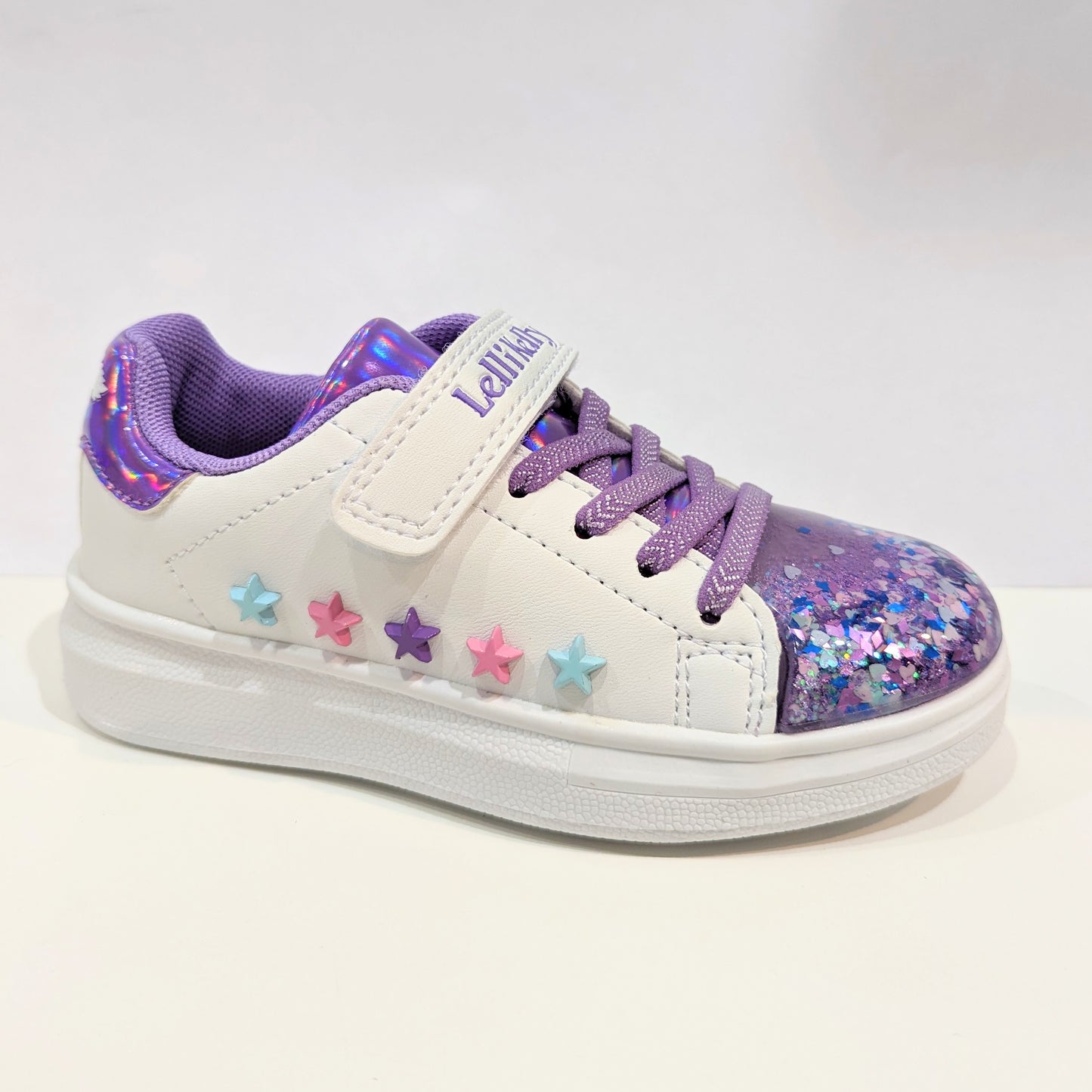 A girls casual trainer by Lelli Kelly, style Helene, in white and lilac leather with faux lace and velcro fastening. Right side view.