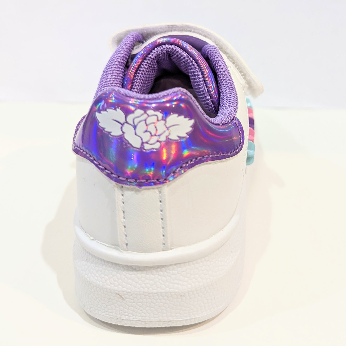 A girls casual trainer by Lelli Kelly, style Helene, in white and lilac leather with faux lace and velcro fastening. Back view.