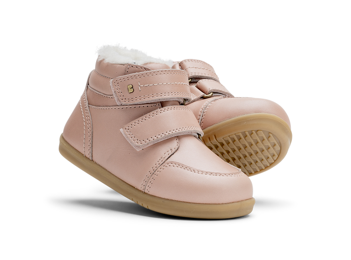 A pair of girls waterproof fur lined ankle boots by Bobux,style Timber, in pale pink with double velcro fastening. Angled view.
