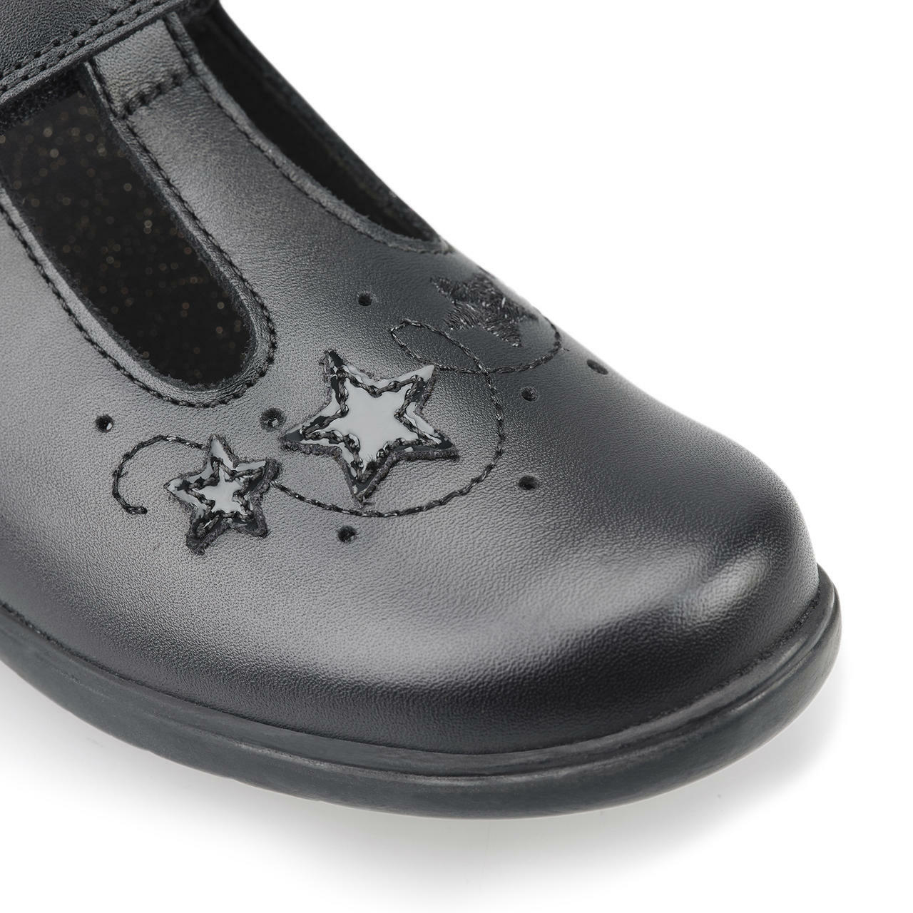 A girls school shoe by Start Rite, style Star Jump, in black leather with star motif and velcro fastening. Close up of star detail.