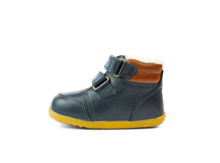 A boys waterproof fur lined ankle boot by Bobux, style Timber Arctic, in Navy and tan leather with double velcro fastening. Left side view.