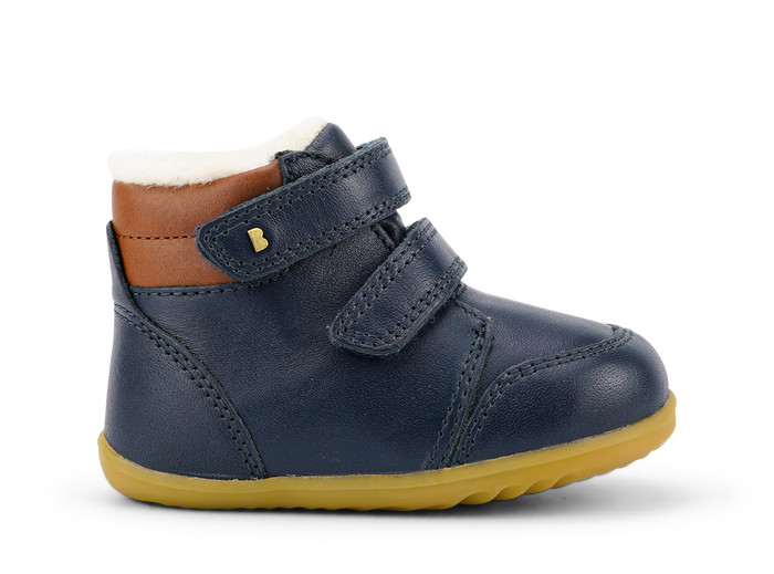 A boys waterproof fur lined ankle boot by Bobux, style Timber Arctic, in Navy and tan leather with double velcro fastening. Right side view.
