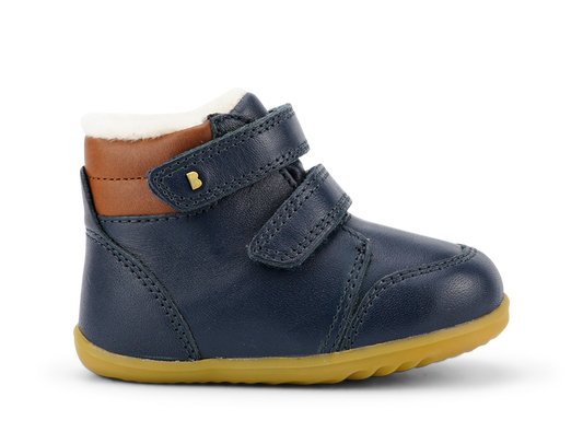 A boys waterproof fur lined ankle boot by Bobux, style Timber Arctic, in Navy and tan leather with double velcro fastening. Right side view.