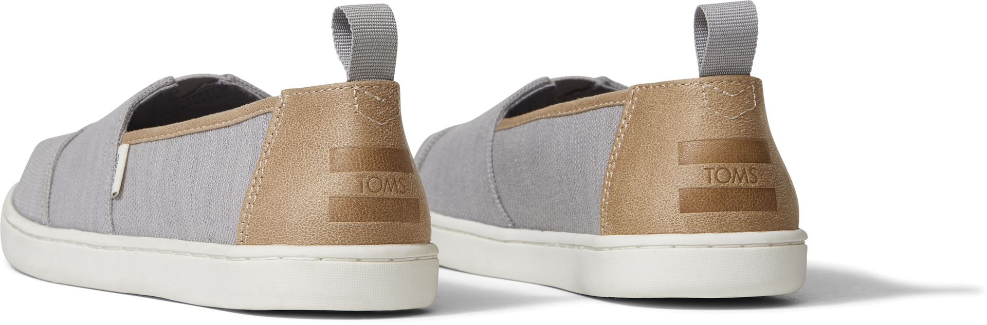 A unisex canvas shoe by TOMS, style Alpargata, a slip on in Grey and Tan. Back view of a pair.