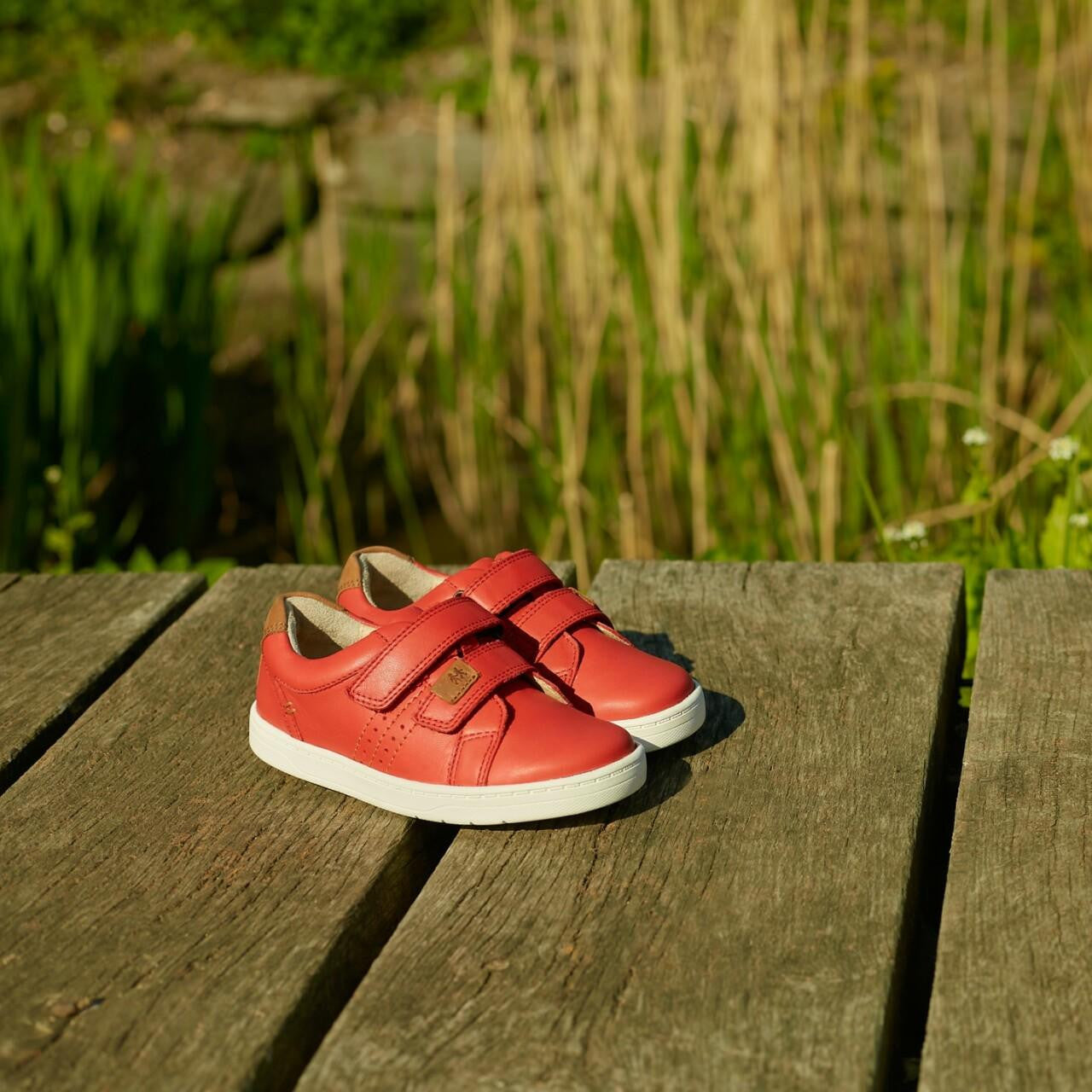 A pair of boys casual shoes by Start Rite, style Explore, in red leather with double velcro fastening. Angled view.