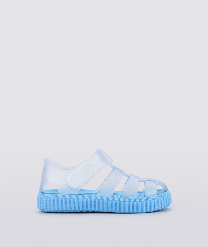 A unisex jelly shoe by Igor, style Nico Cristal, in clear with a blue sole and velcro strap. Right side view.