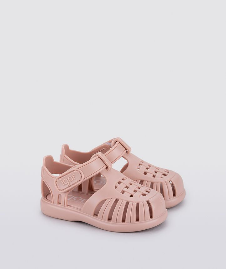A girls jelly shoe by Igor, style Tobby Solid, in pink with a velcro strap. Angled view of a pair.