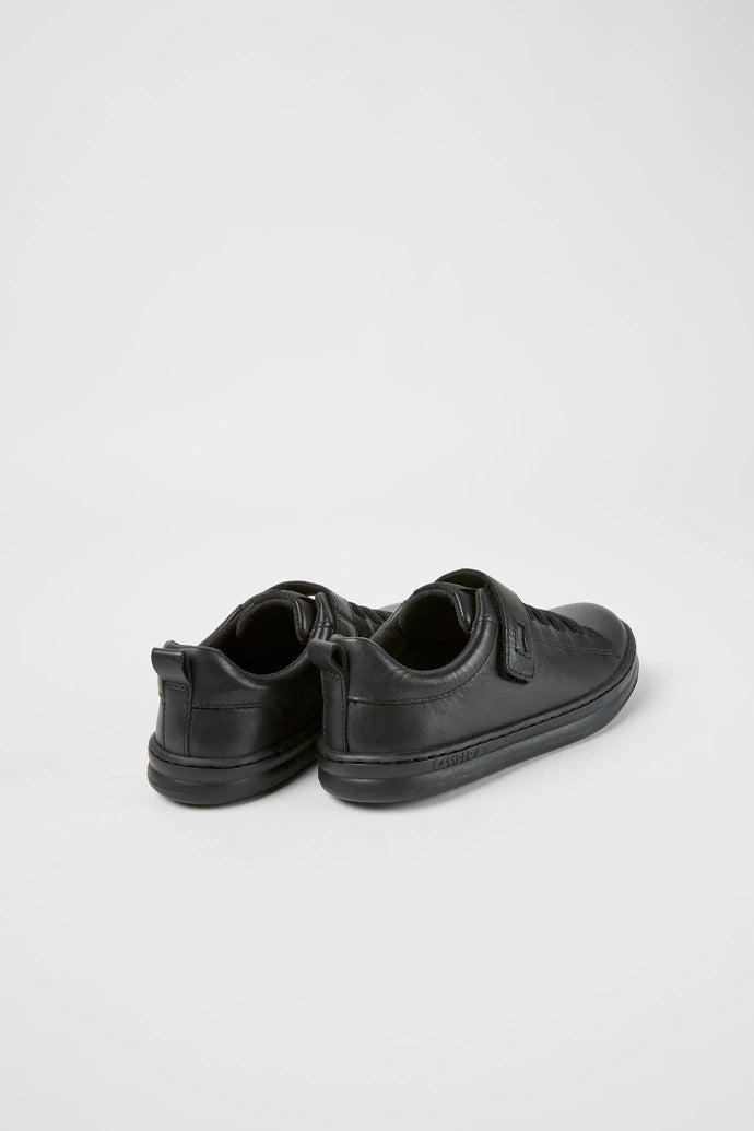 A boys casual school shoe by Camper,style K800319-001 in black leather with faux lace and zip fastening. Angled view.