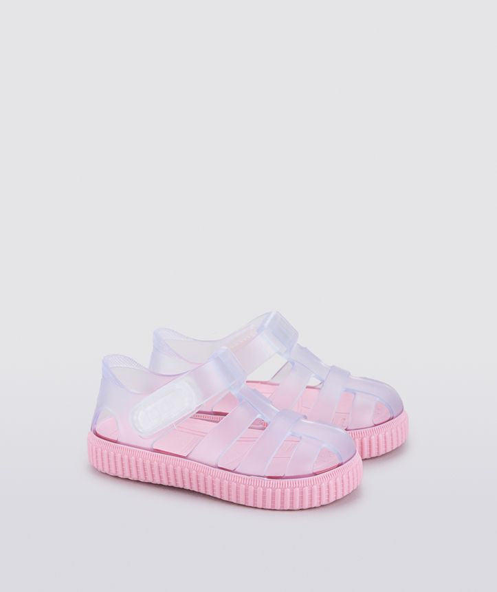 A girls Jelly shoe by Igor, in clear with a pink sole, velcro fastening. Side view of a pair.