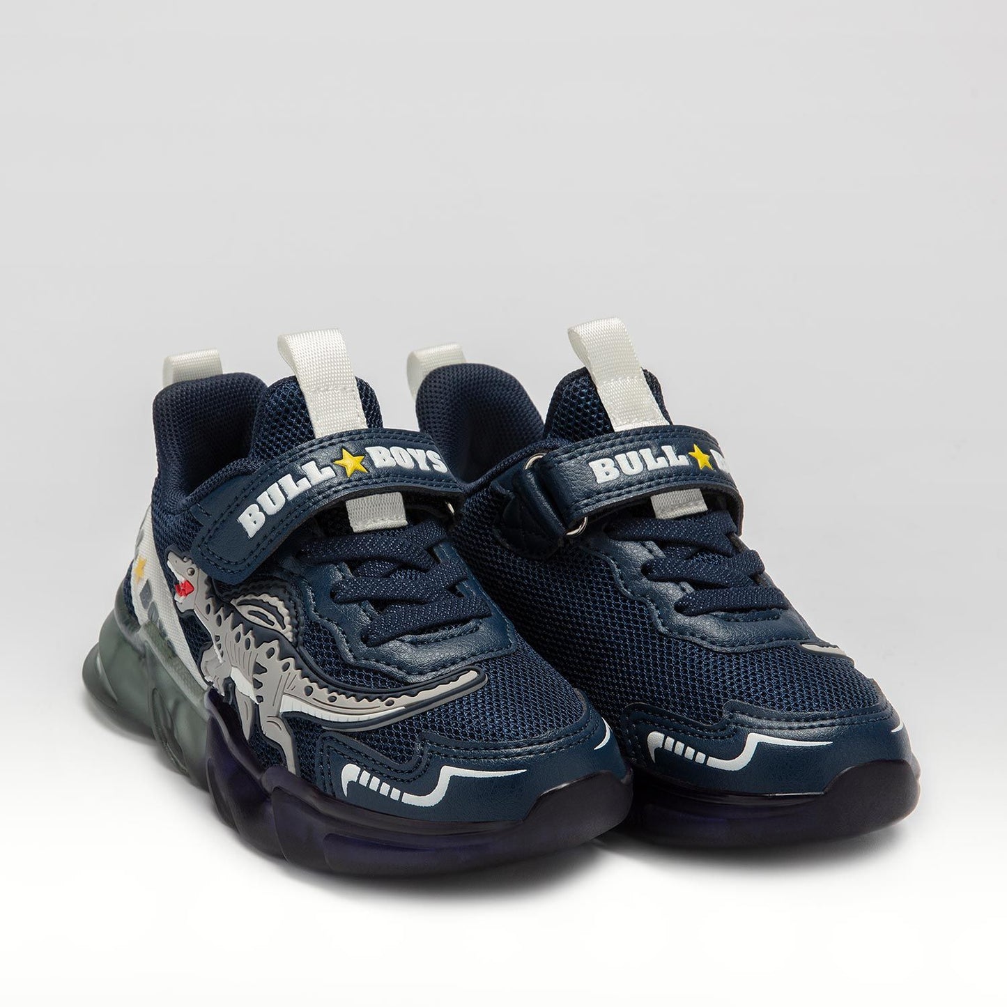 A pair of boys trainer by Bull Boys, style Spinosauro, in navy blue with grey dinosaur in 3D and flashing sole. Velcro and elastic faux lace fastening. 